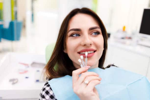 Girl chooses color of veneers at the dentist office